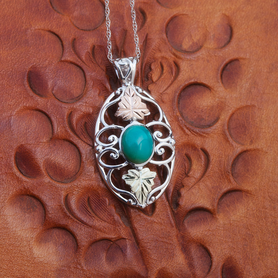 Western style turquoise filligree scroll pendant with two hand-placed Black Hills Gold grape leaves. Necklace is  18 inches long.